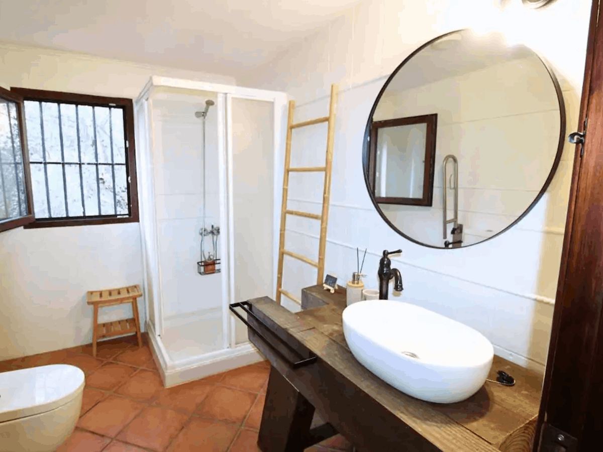 Primer baño: ducha con mampara de cristal y lavabo sobre encimera de madera