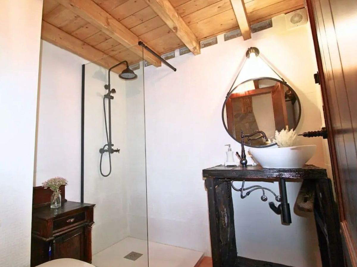Segundo baño de la casa, con ducha de obra y techo de vigas de madera