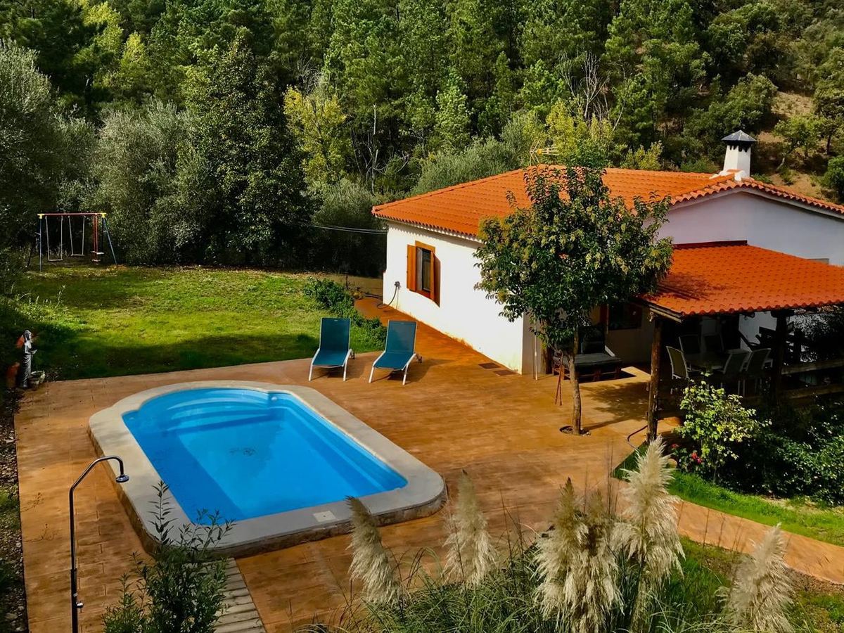La casa y la piscina privada, rodeadas por el bosque de la finca